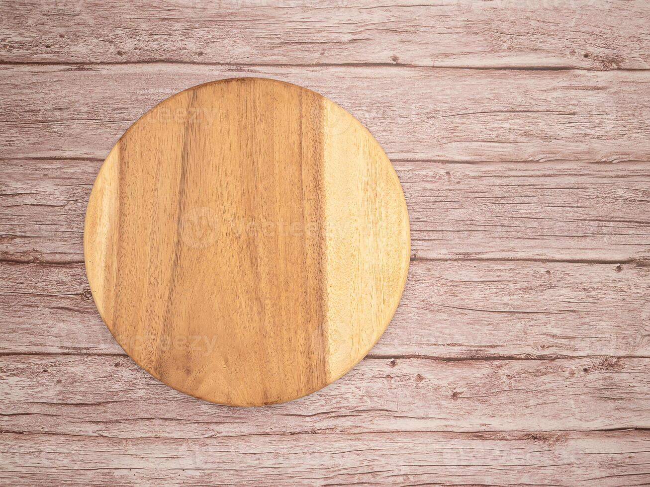 Top view of a blank round wooden cutting board over a wooden table photo