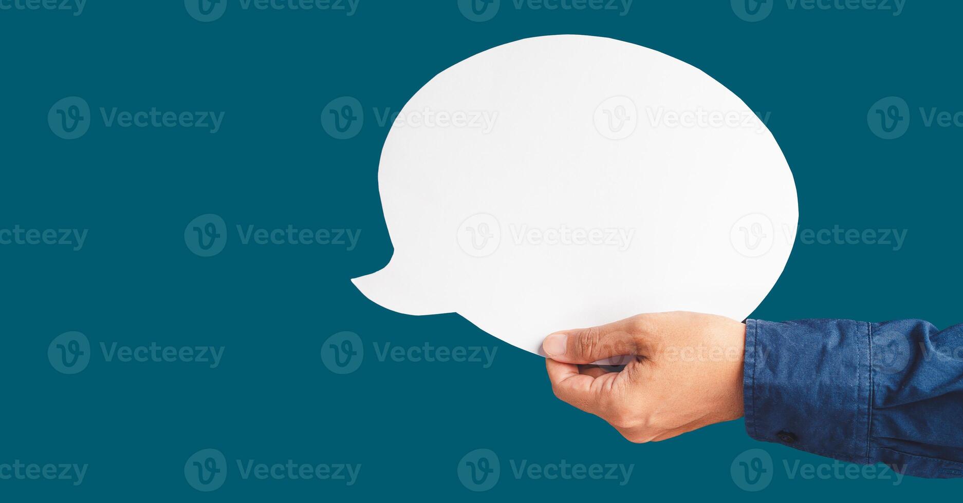 Close-up of hand holding a white speech bubble against a blue background photo