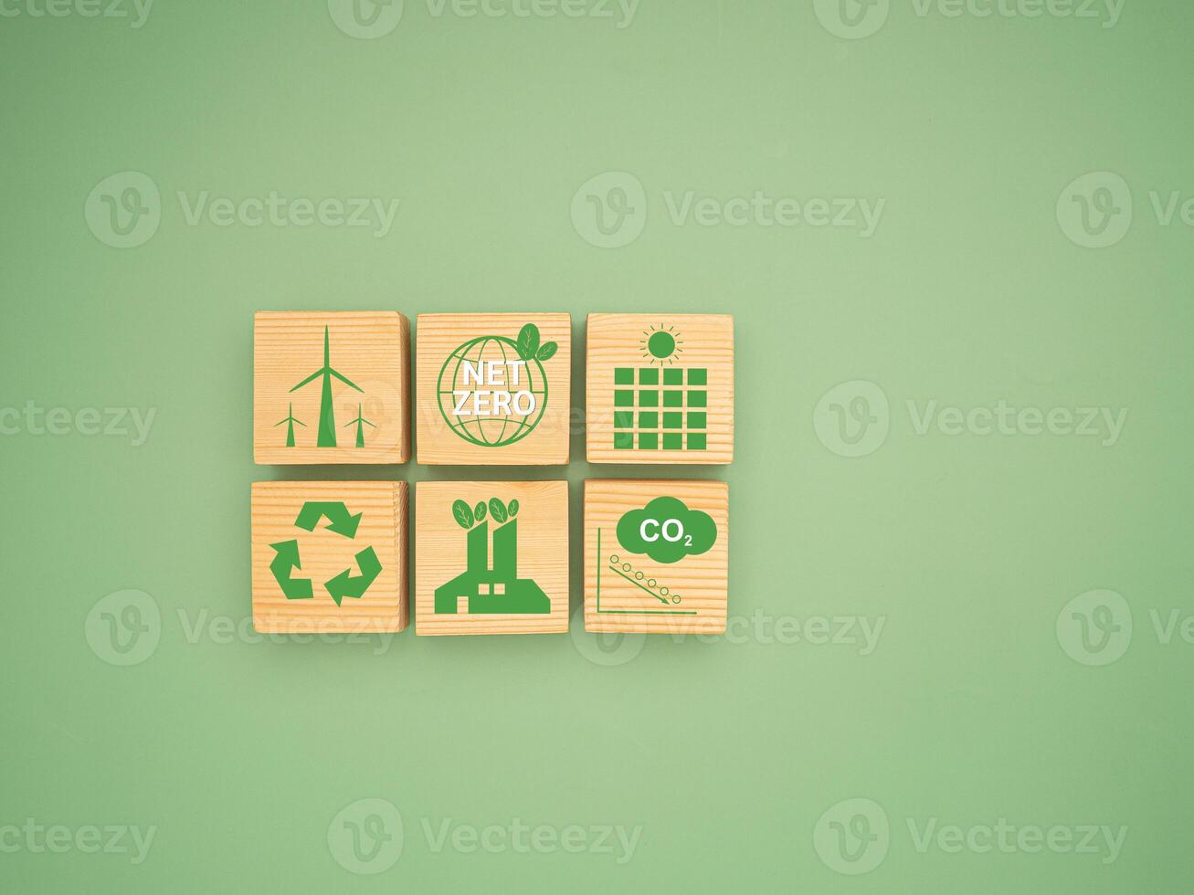 Net-zero greenhouse gas emissions target. Wooden cubes with green icons over a green background photo
