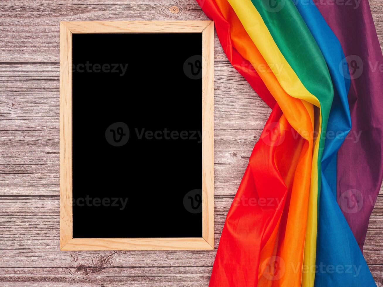 Top view of the rainbow flag or LGBT and a blank mini chalkboard with the wooden border over a cement floor photo