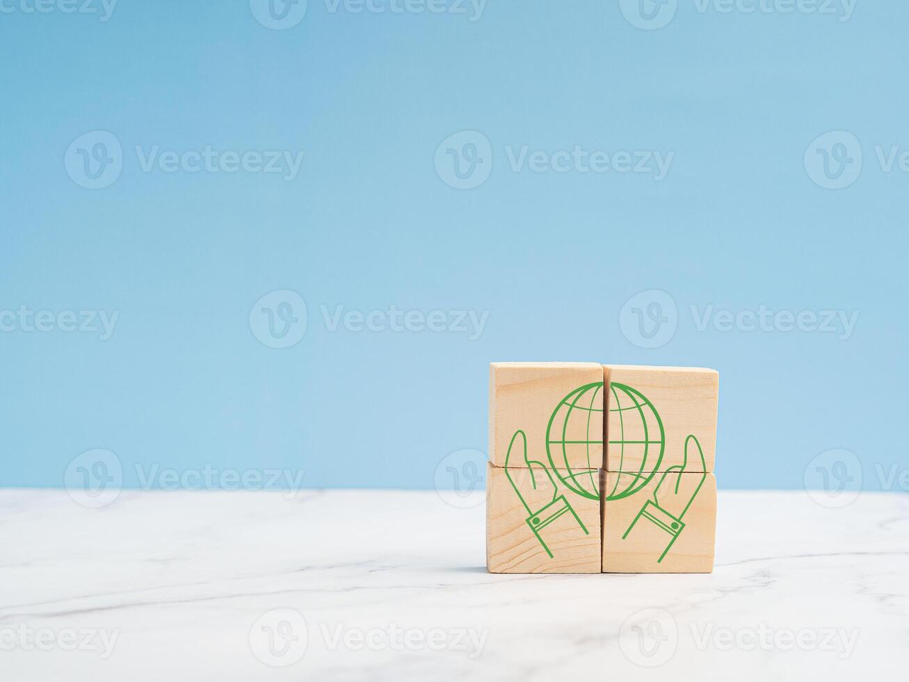 Save Earth Concept. Wooden cubes with the world green icons and two hands over a marble floor against a blue background photo