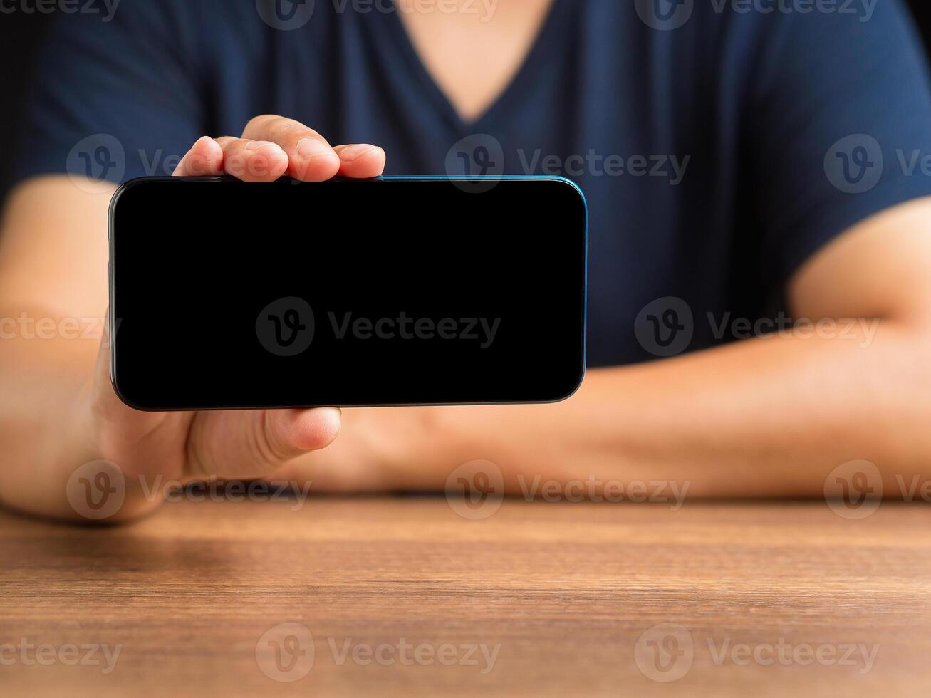 Hand holding a blank screen smartphone while sitting at the table photo