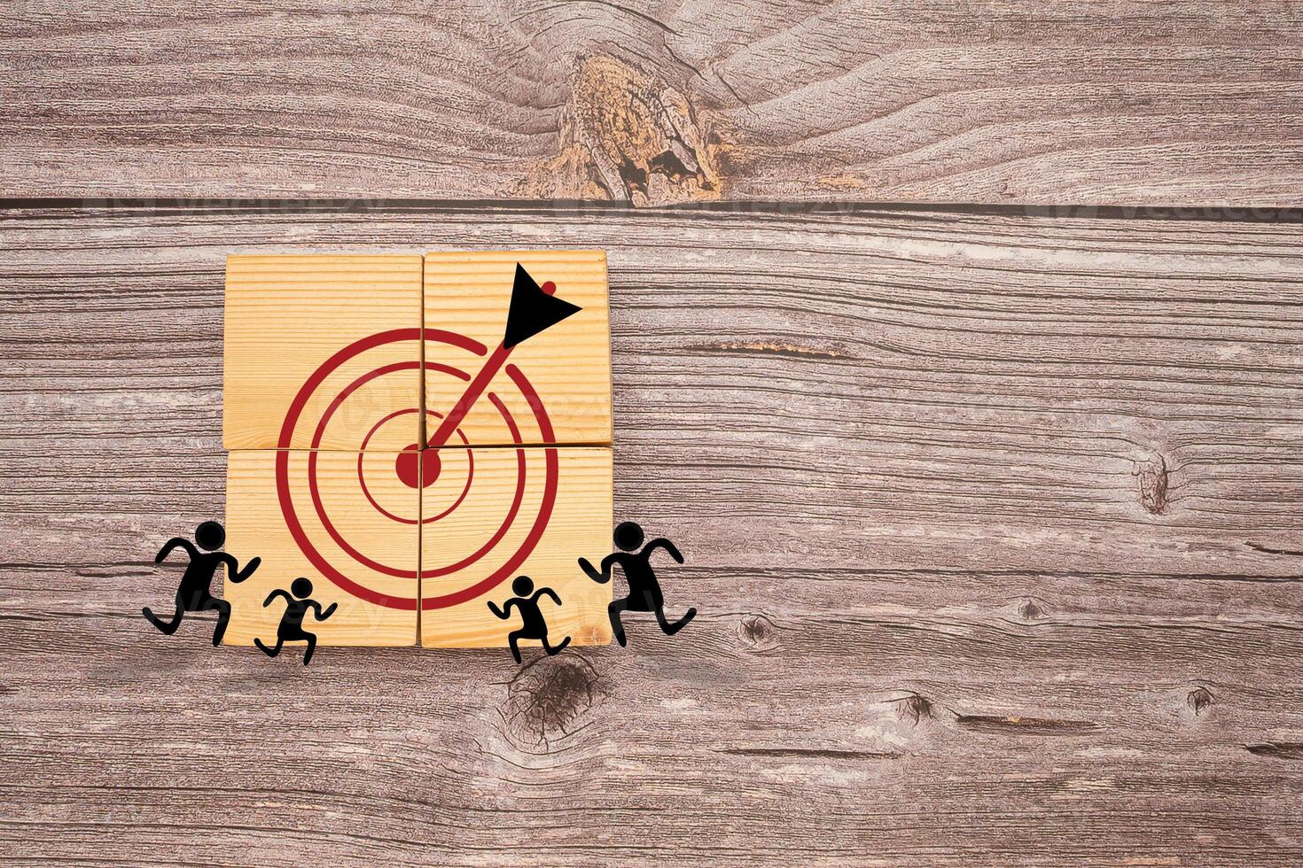 Darts target icons on wooden cubes with people icons on a wooden table photo