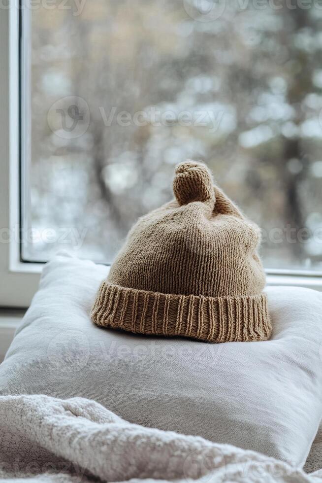 Cozy Winter Scene with Knitted Hat on Pillow by Window Overlooking Snowy Landscape photo