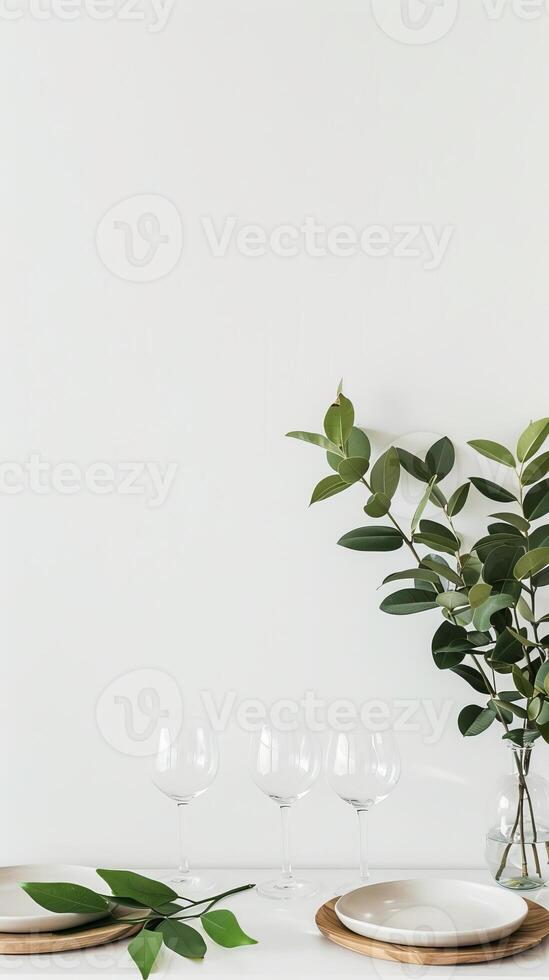 A table with a vase of green leaves and four wine glasses photo
