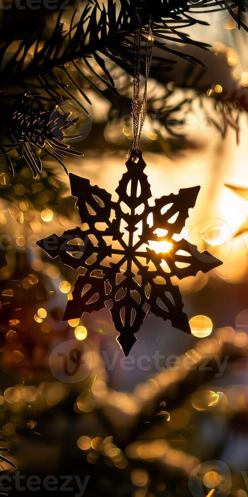 A snowflake ornament hangs from a tree photo
