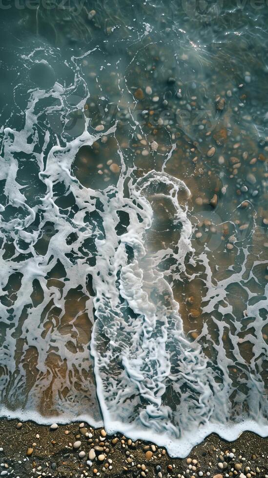 Aerial View of Ocean Waves Gently Crashing on a Pebble Beach photo