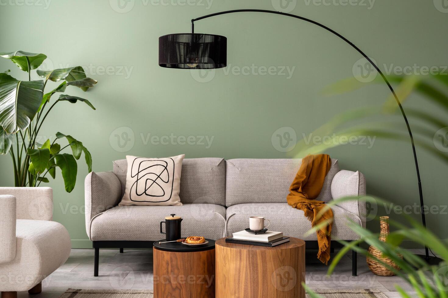 The stylish composition at living room interior with green wall, design gray sofa, coffee table, dark lamp and elegant personal accessories. Beige pillow and plaid. Cozy apartment. Template. photo