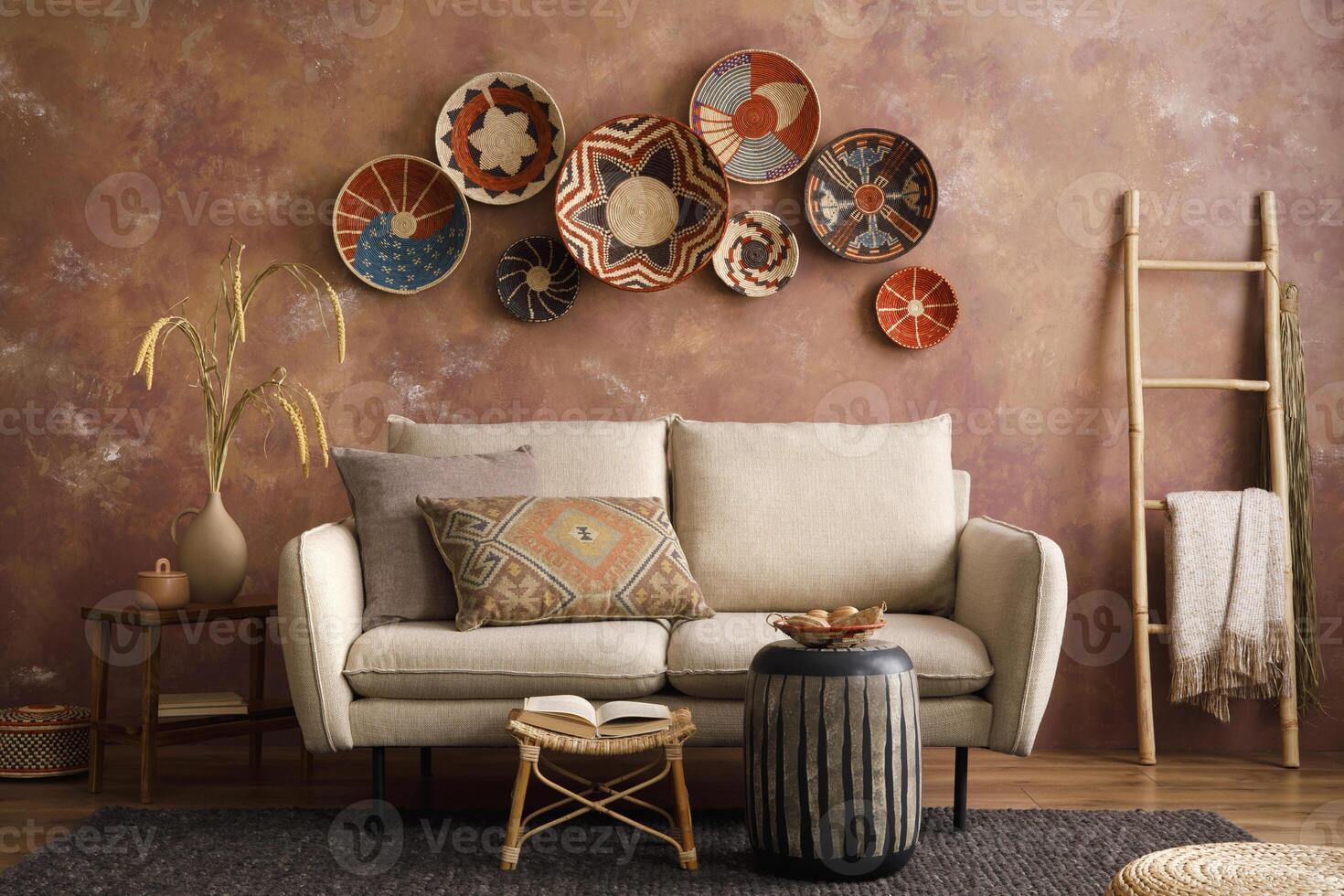 The stylish boho compostion at living room interior with design beige sofa, coffee table, stool wicker baskets and personal accessories. Brown and white pillows and plaid. Cozy apartment. Home decor. photo