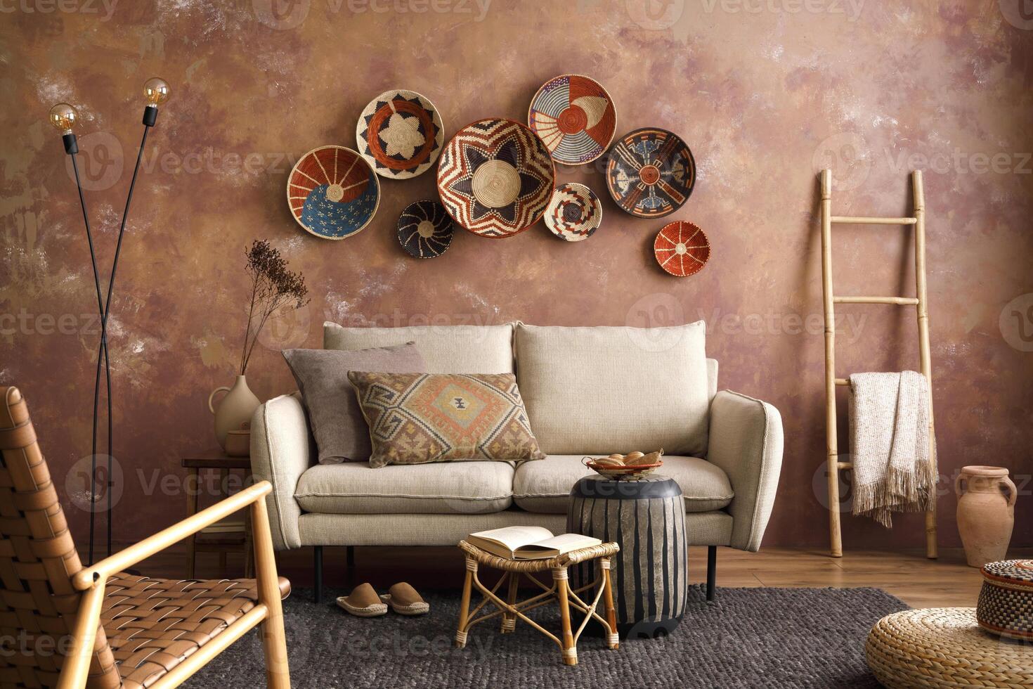 The stylish boho compostion at living room interior with design beige sofa, coffee table, wicker baskets and elegant personal accessories. Brown and white pillows and plaid. Cozy apartment. Home decor photo