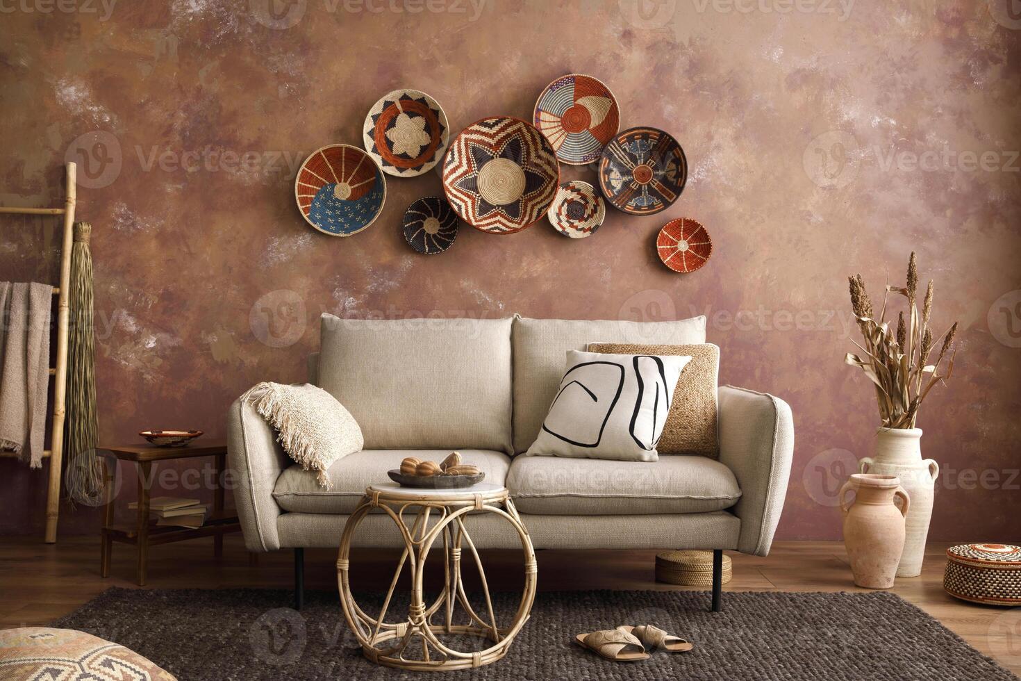 The stylish boho compostion at living room interior with design beige sofa, coffee table, stool wicker baskets and personal accessories. beige and white pillows. Cozy apartment. Template. photo