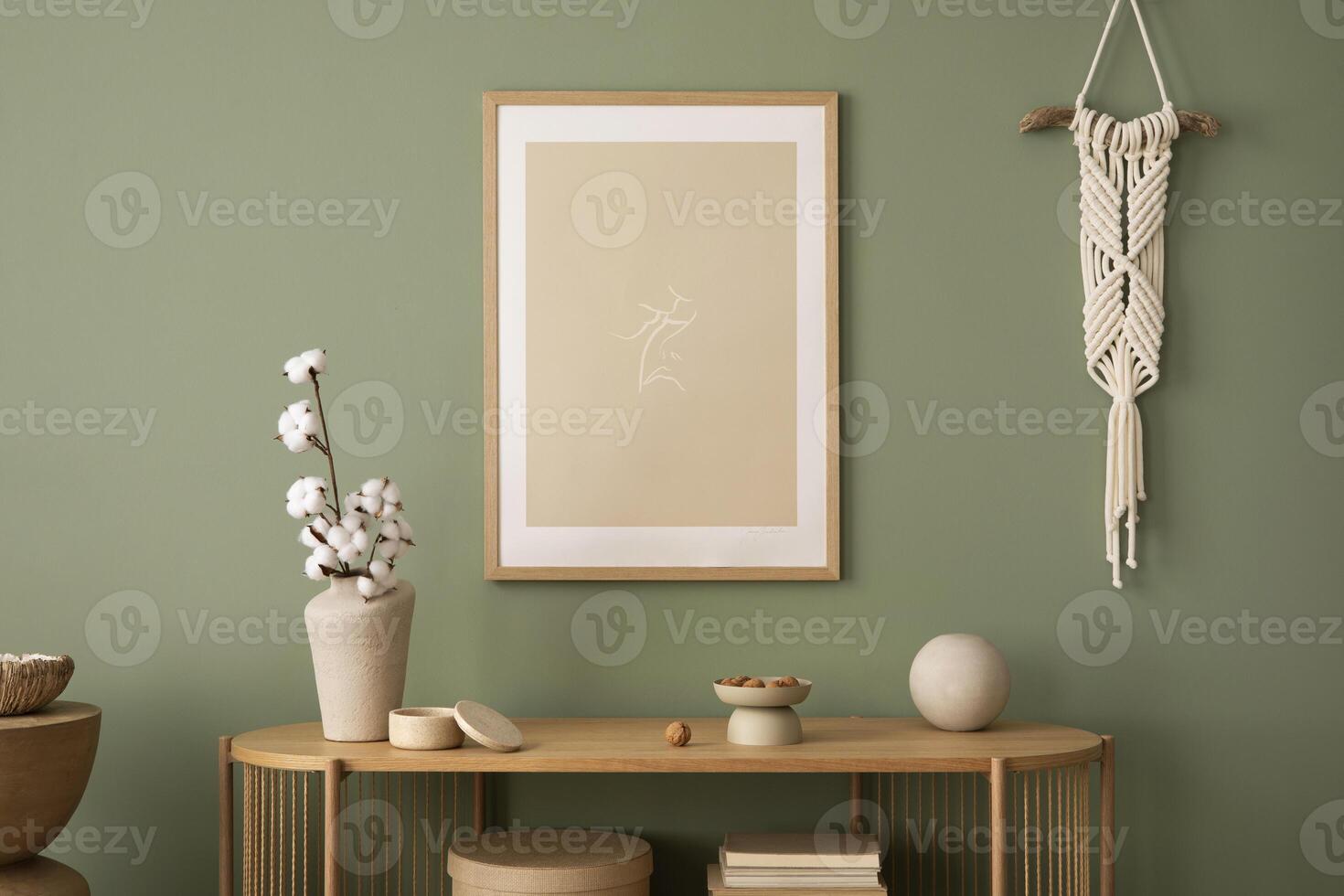 Stylish living room interior design with mock up poster frames, macrame, wooden chest of drawers, beige vase and creative home accessories. Sage green wall. Template. photo