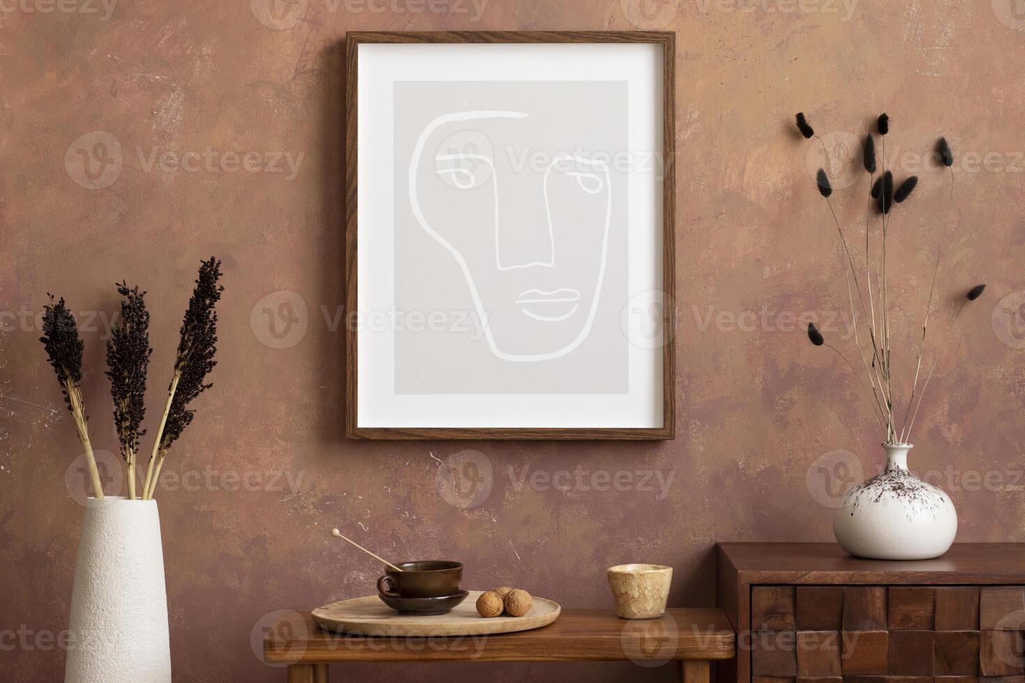 Creative composition retro living room interior with mock up poster frame, stylish wooden consola, vase with dried flowers, trace with cup, almonds, brown wall and personal accessories. Home decor. photo