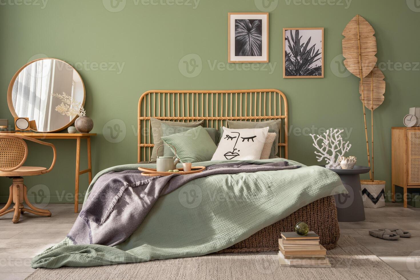 Stylish bedroom interior design with mock up poster frames, bed, side table, rattan commode, vanity table and creative home accessories. Sage green wall. Template. Copy space. photo