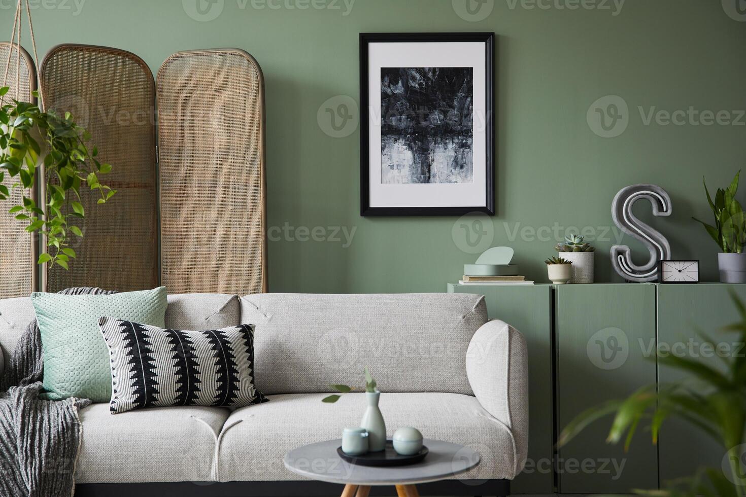 Elegant living room interior design with mockup poster frame, modern grey sofa, wooden commode, folding screen, plants and stylish accessories. Eucalyptus wall. Template. Copy space. photo