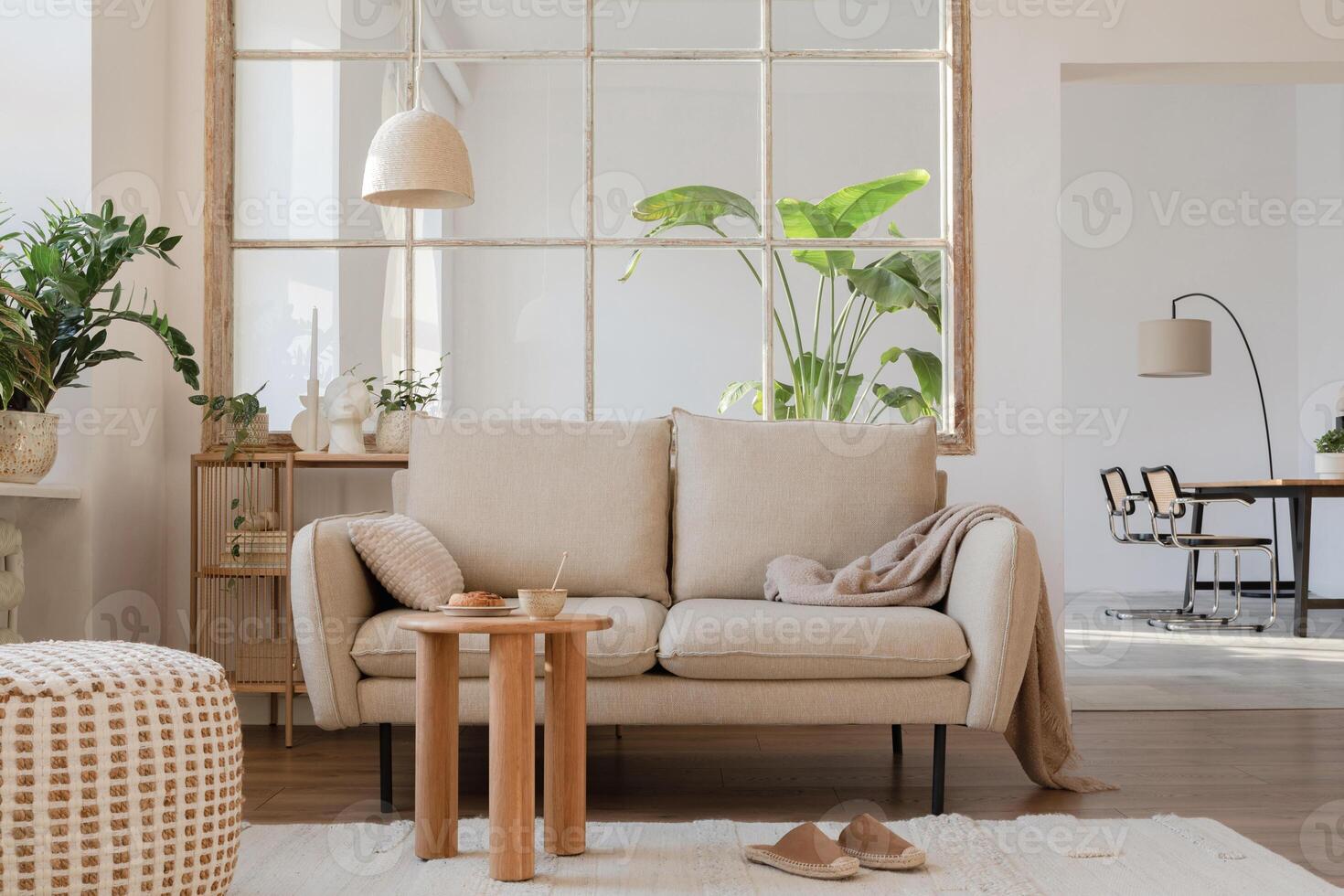 Elegant living room interior design with beige modern sofa, side table and creative accessories. Template. Copy space. Dining room in the background. photo