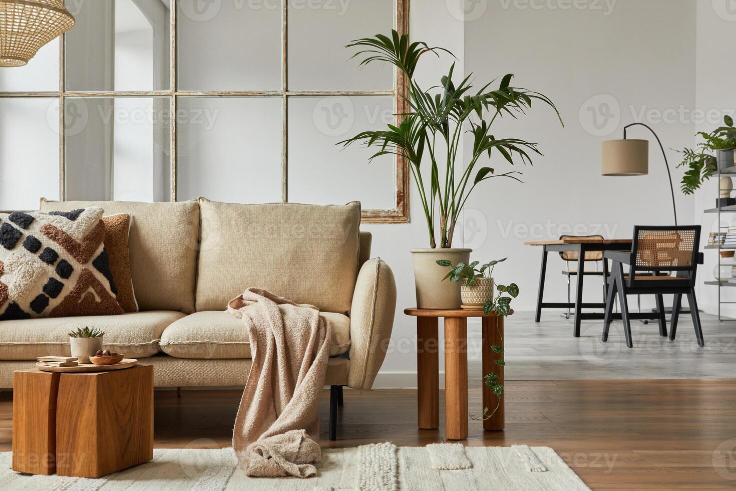 Modern living room interior design with beige sofa, wooden side table, plants and creative accessories. Template. Copy space. Dining room in the background photo