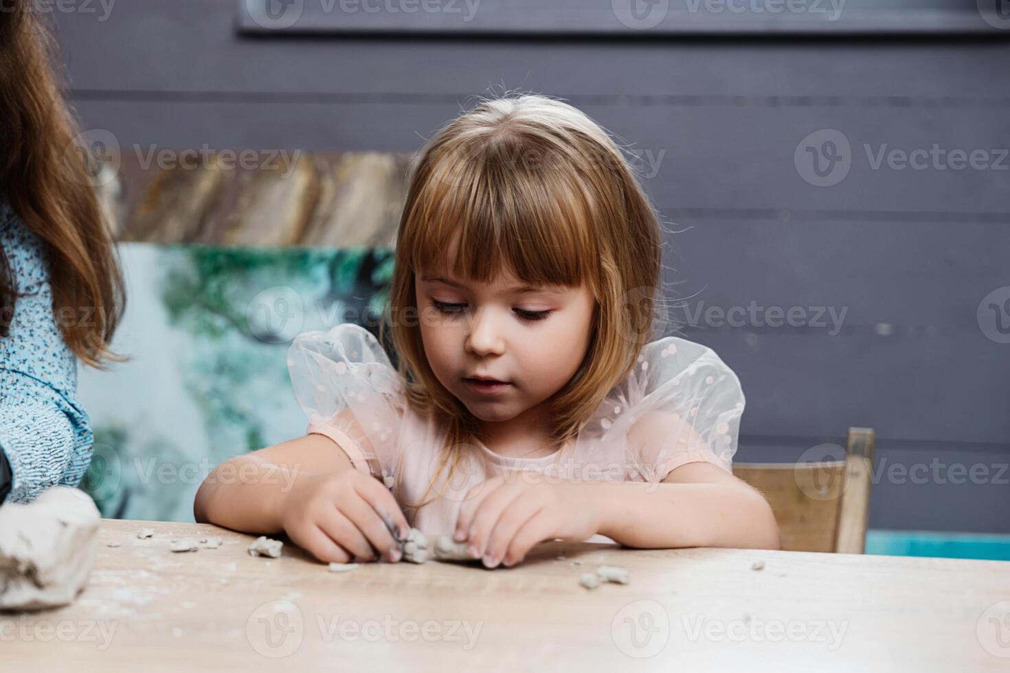child engaged in creative play with clay at a table indoors photo