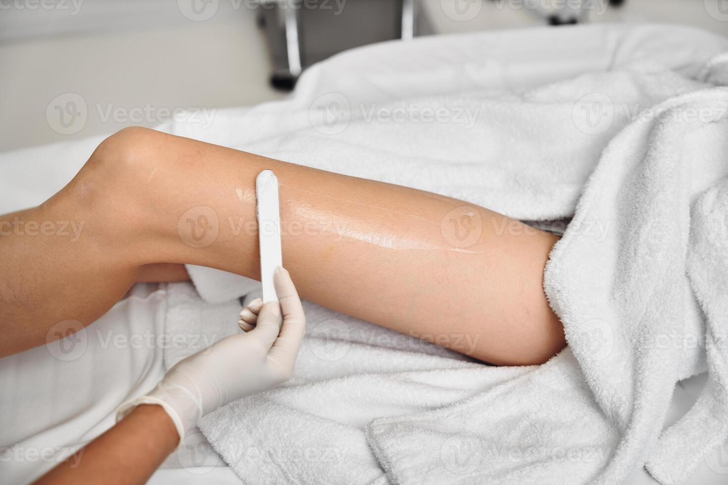 Waxing treatment on a clients leg in a clean salon setting in daylight photo