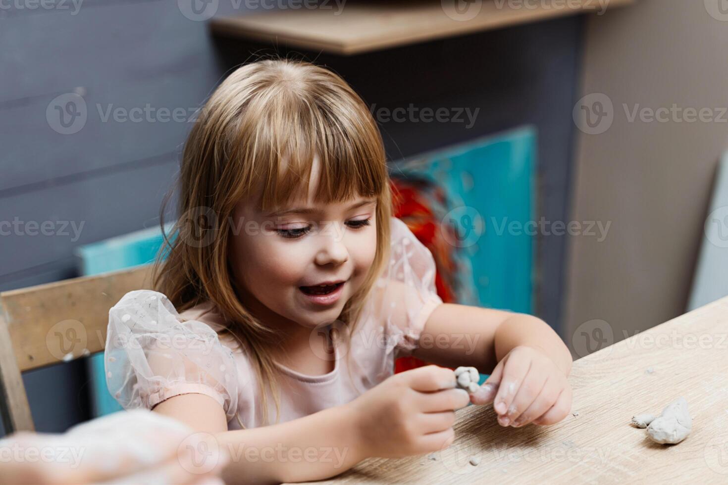 Girl engaged in creative play with modeling clay at a craft table photo