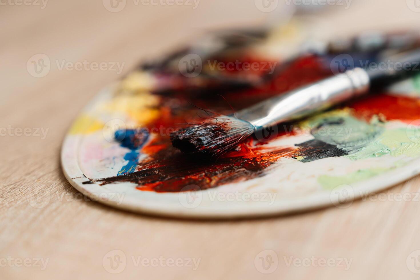 Colorful paint palette with brushes resting on a wooden surface photo
