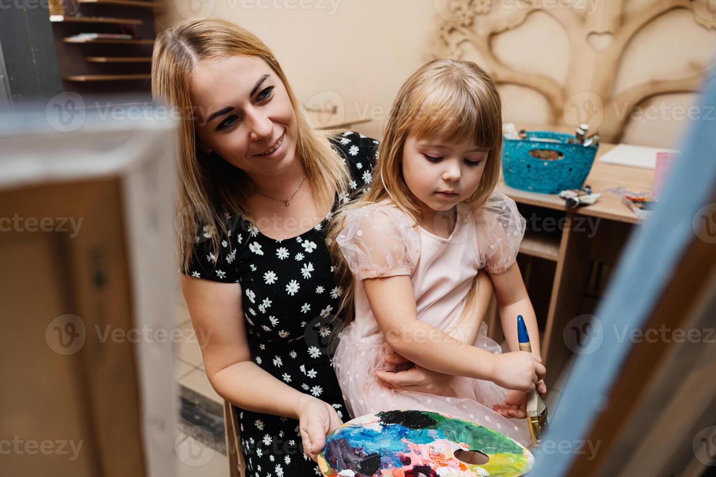 Mother and daughter enjoying a creative painting session indoors photo
