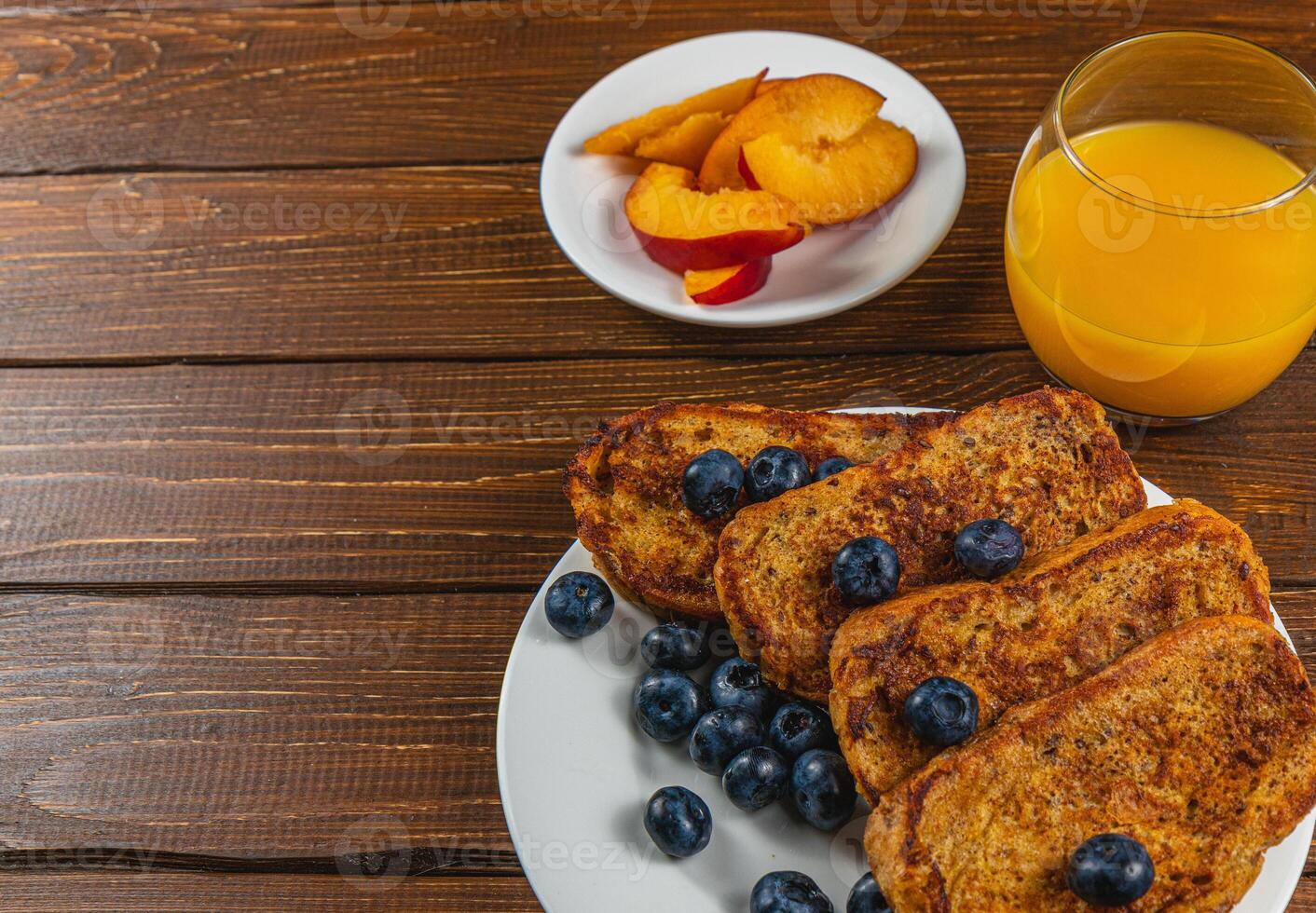 French toast on a plate with blueberries, orange juice, nectarine for breakfast photo