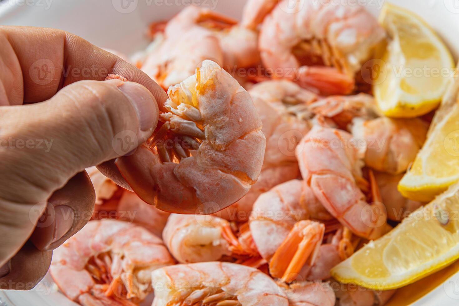 Tiger king prawns cooked and seasoned with lemon, close up in a man's fingers photo