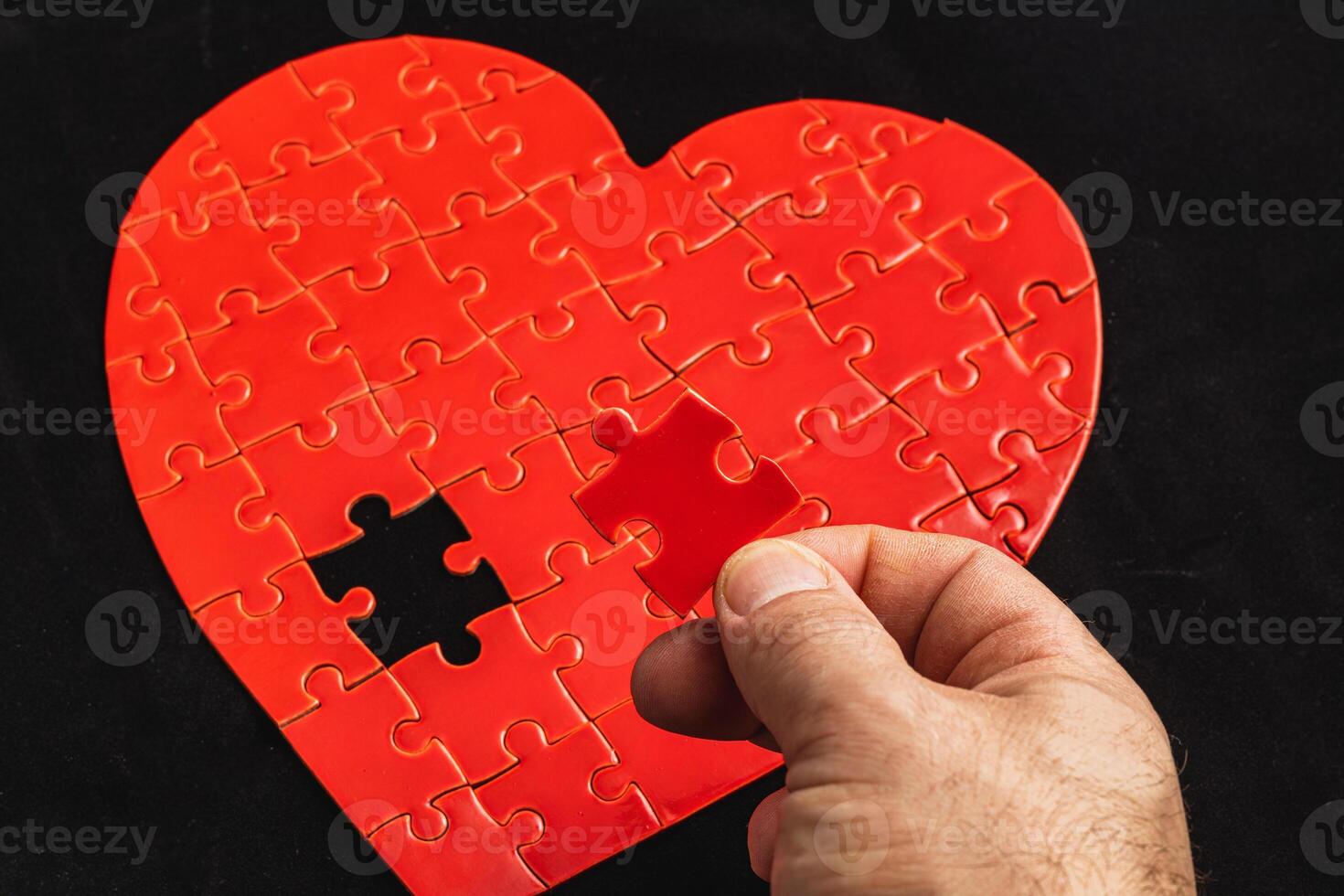 Concept of feelings in a puzzle. Hand puts missing pieces into a heart puzzle photo
