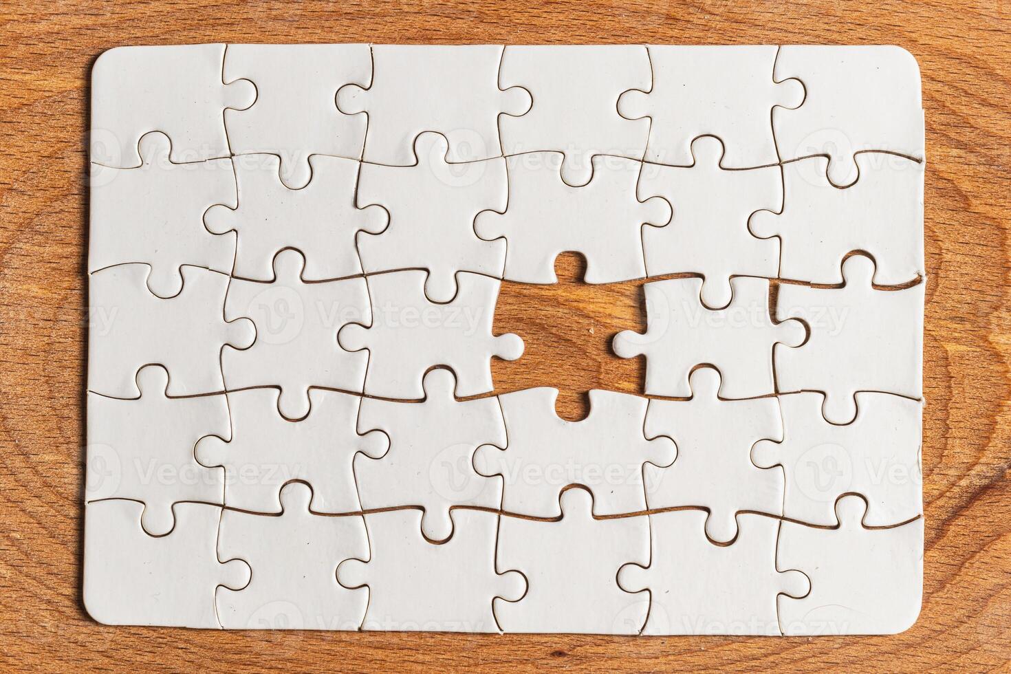 White puzzle with missing piece on wooden background photo