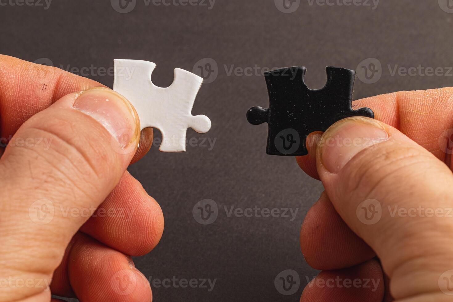 Hands holding black and white puzzle, concept of difficult option choice photo