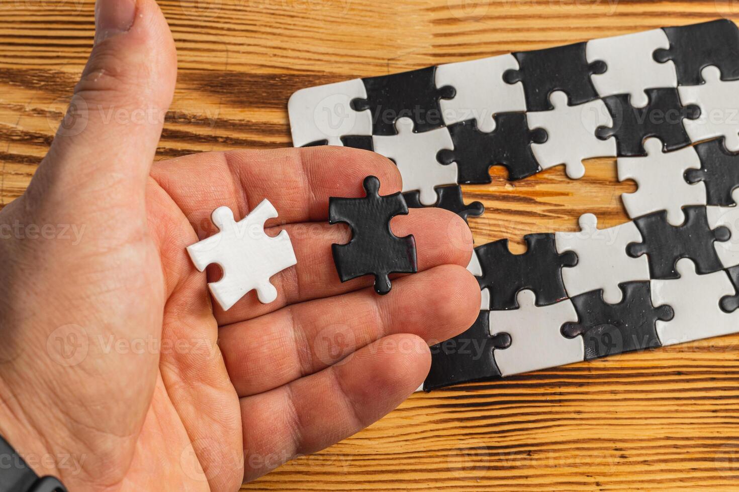 Hands holding black and white puzzle, concept of difficult option choice photo