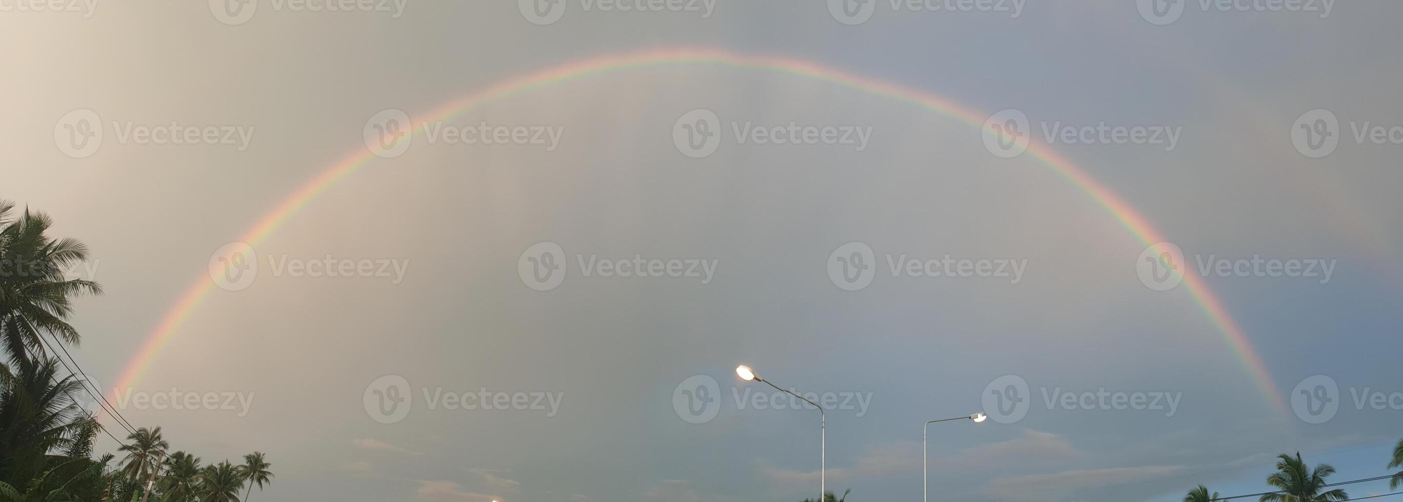 Vibrant rainbow appears after rain coastal road scenic photograph tropical environment wide angle nature beauty photo