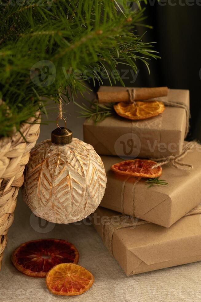 Gifts packed in brown craft paper, decorated with orange and cinnamon and green Christmas tree branches, close-up photo