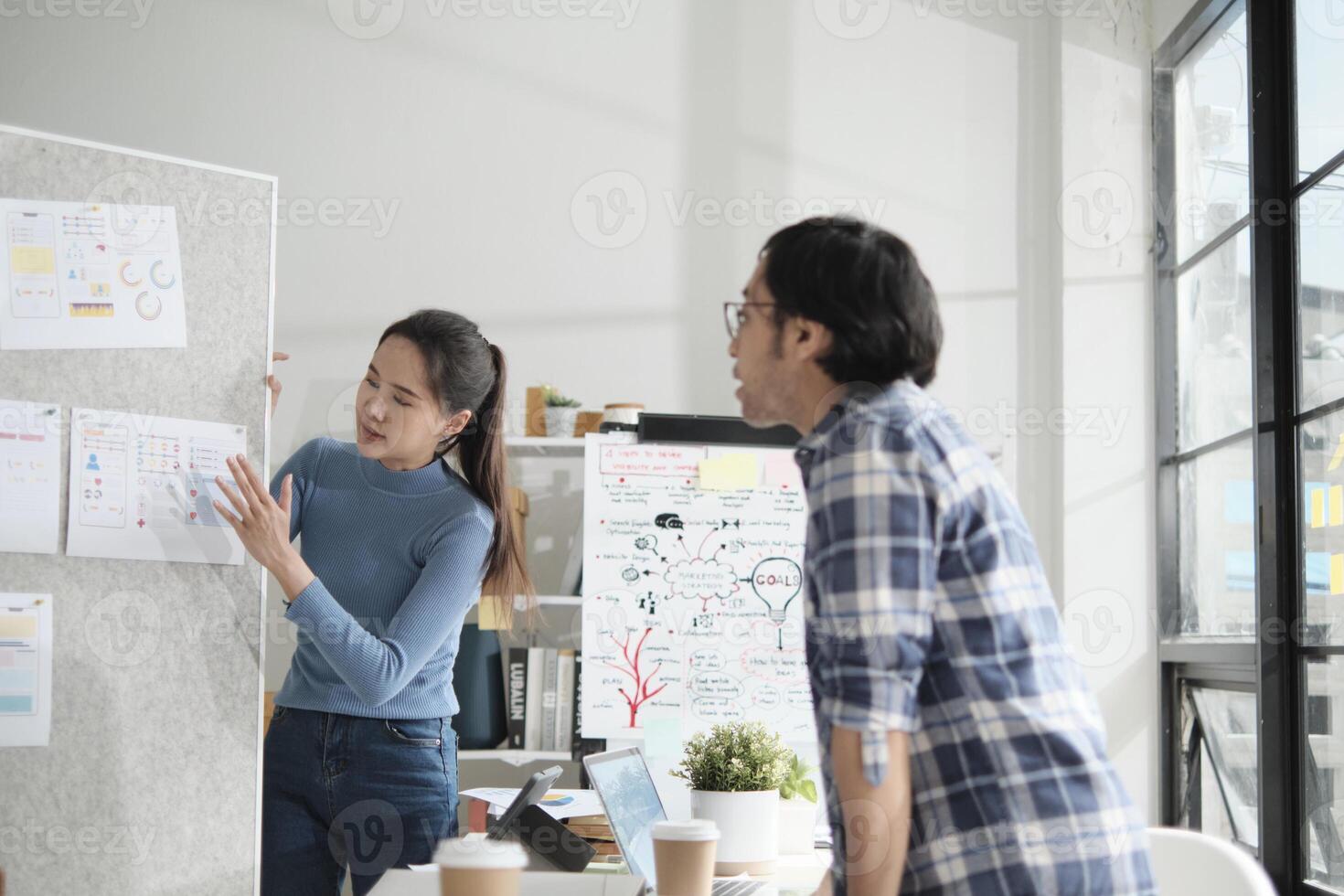 Two young Asian startup company partners discuss and brainstorm in casual small business office, marketing planning ideas, and creatively freelance work as E-commerce entrepreneur and coworker team. photo