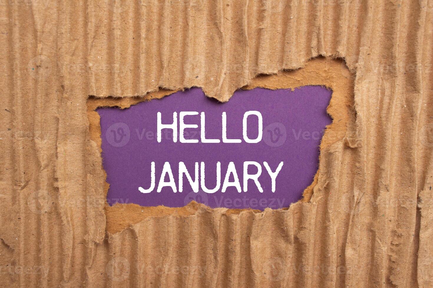 Hello january message written on ripped torn cardboard paper with purple background. Conceptual hello january symbol. Copy space. photo
