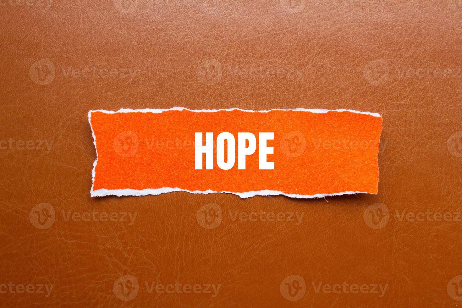 Hope message written on ripped orange torn paper piece with brown background. Conceptual hope symbol. Copy space. photo
