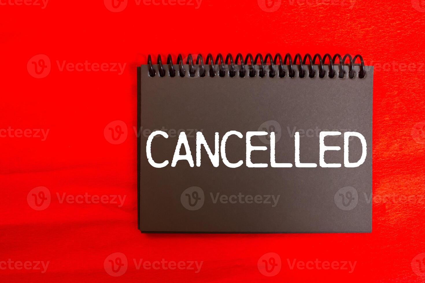 Cancelled message written on black notebook page with red background. Conceptual cancelled symbol. Copy space. photo