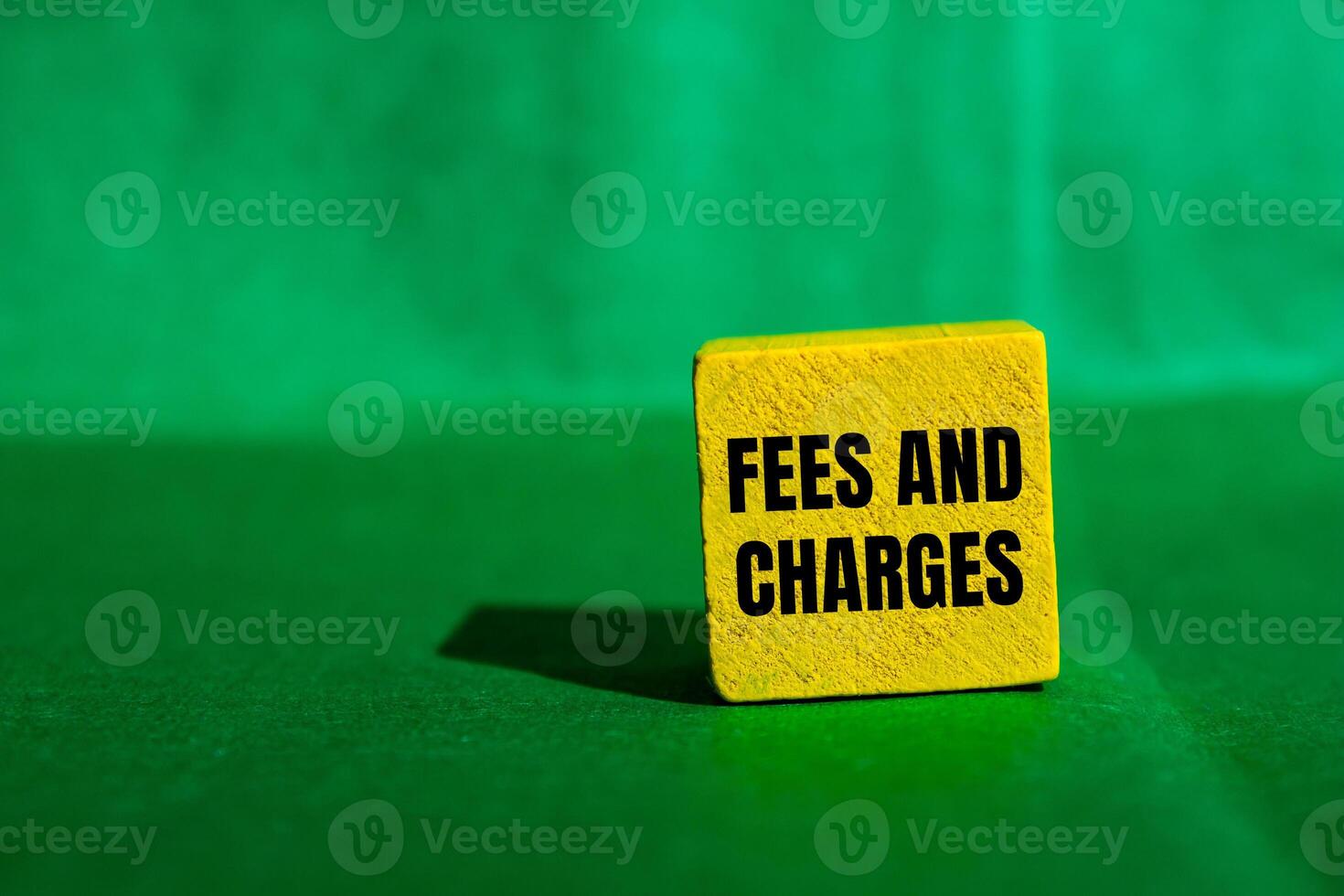 Fees and charges message written on yellow wooden cube with green background. Conceptual fees and charges symbol. Copy space. photo