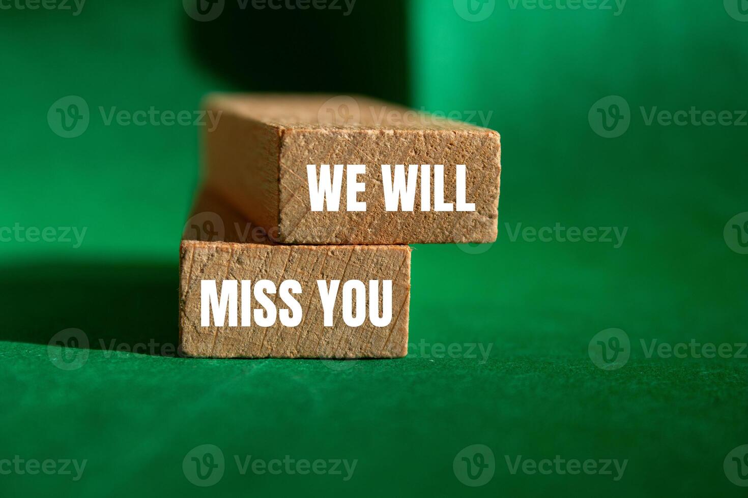 We will miss you message written on wooden blocks with green background. Conceptual we will miss you symbol. Copy space. photo