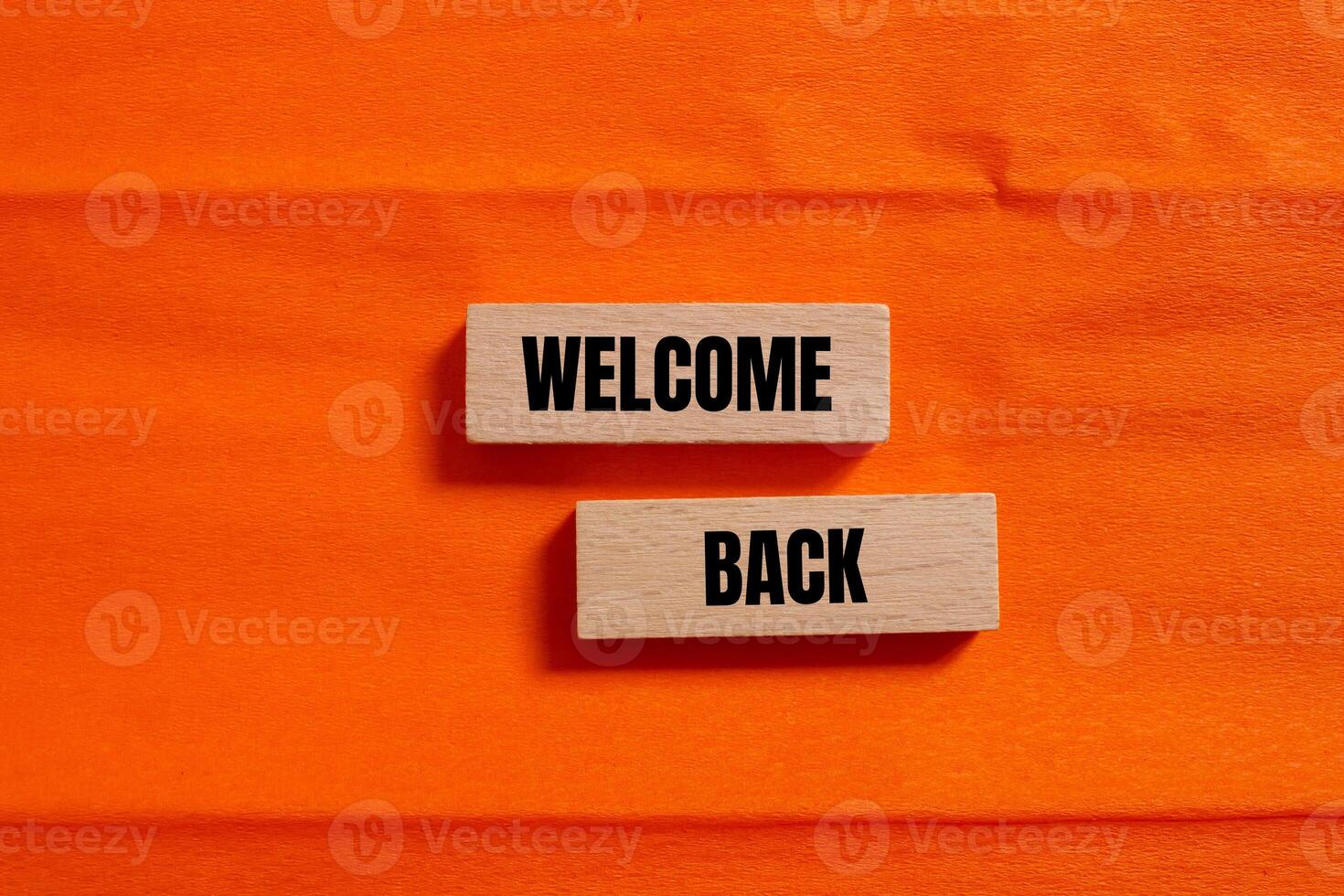 Welcome back message written on wooden blocks with orange background. Conceptual welcome back symbol. Copy space. photo