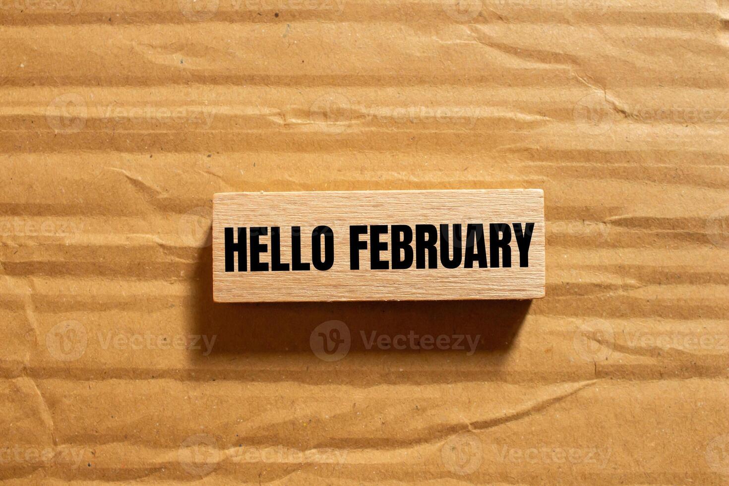 Hello february message written on wooden block with cardboard background. Conceptual hello february symbol. Copy space. photo