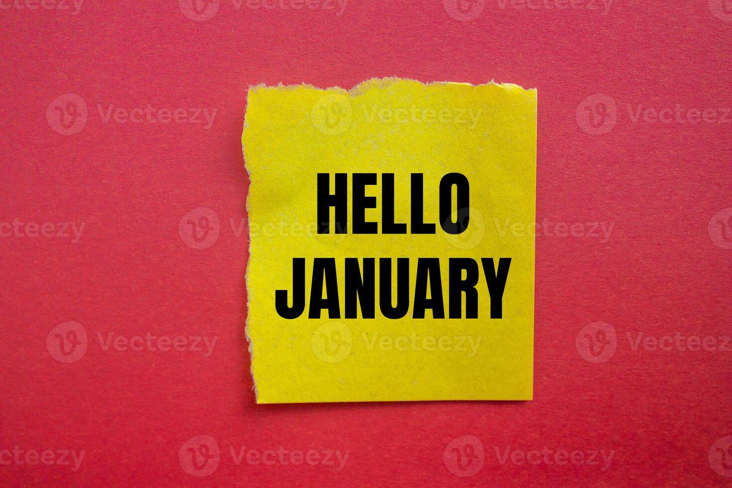 Hello january message written on ripped torn yellow paper piece with red background. Conceptual hello january symbol. Copy space. photo