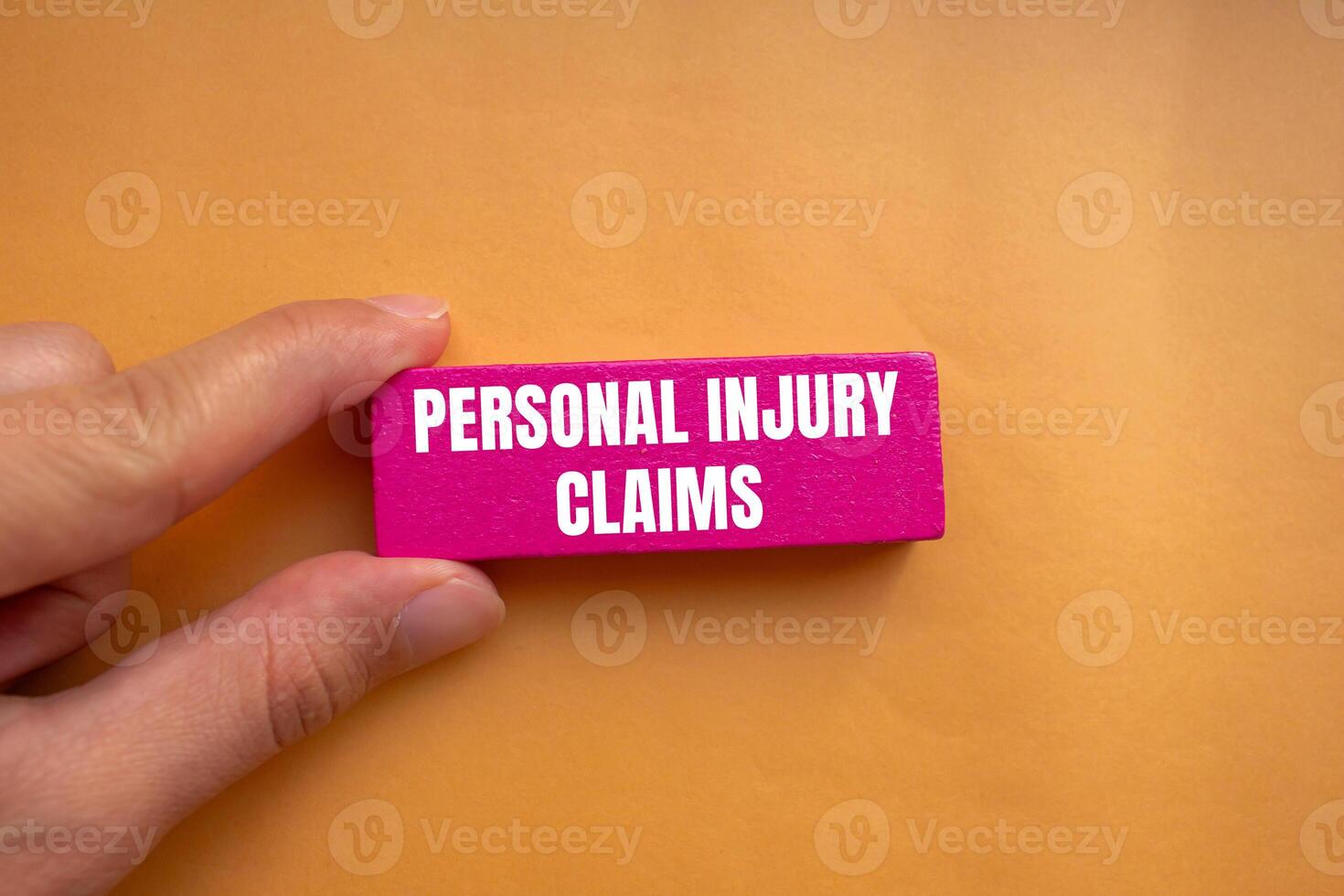 Personal injury claims message written on pink wooden block with orange background. Conceptual personal injury claims symbol. Copy space. photo