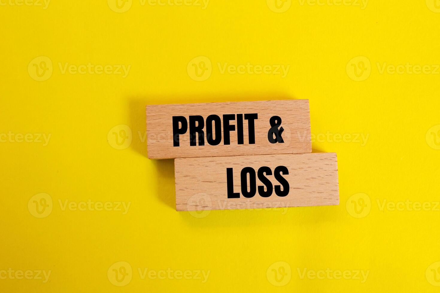 Profit and loss message written on wooden blocks with yellow background. Conceptual profit and loss symbol. Copy space. photo