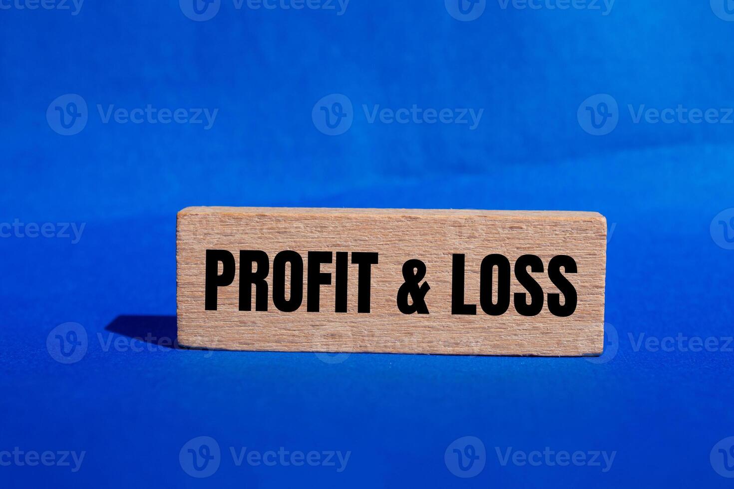 Profit and loss message written on wooden block with blue background. Conceptual profit and loss symbol. Copy space. photo