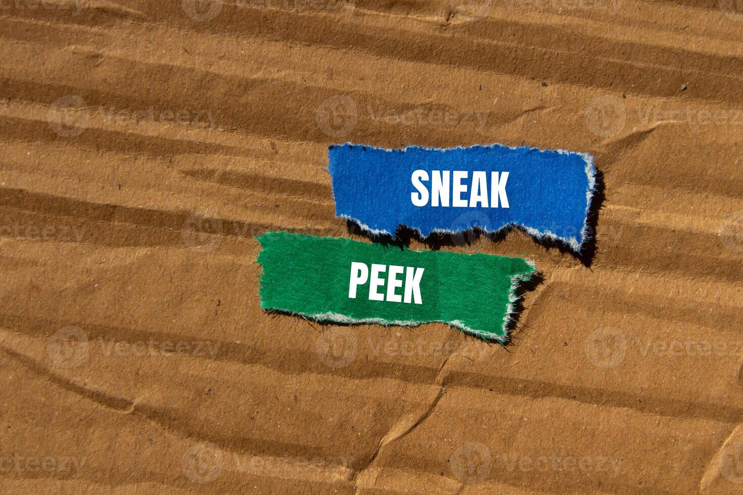 Sneak peek message written on ripped torn paper pieces with cardboard background. Conceptual sneak peek symbol. Copy space. photo