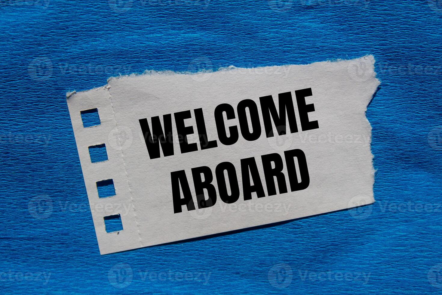 Welcome aboard message written on ripped torn paper piece with blue background. Conceptual welcome aboard symbol. Copy space. photo