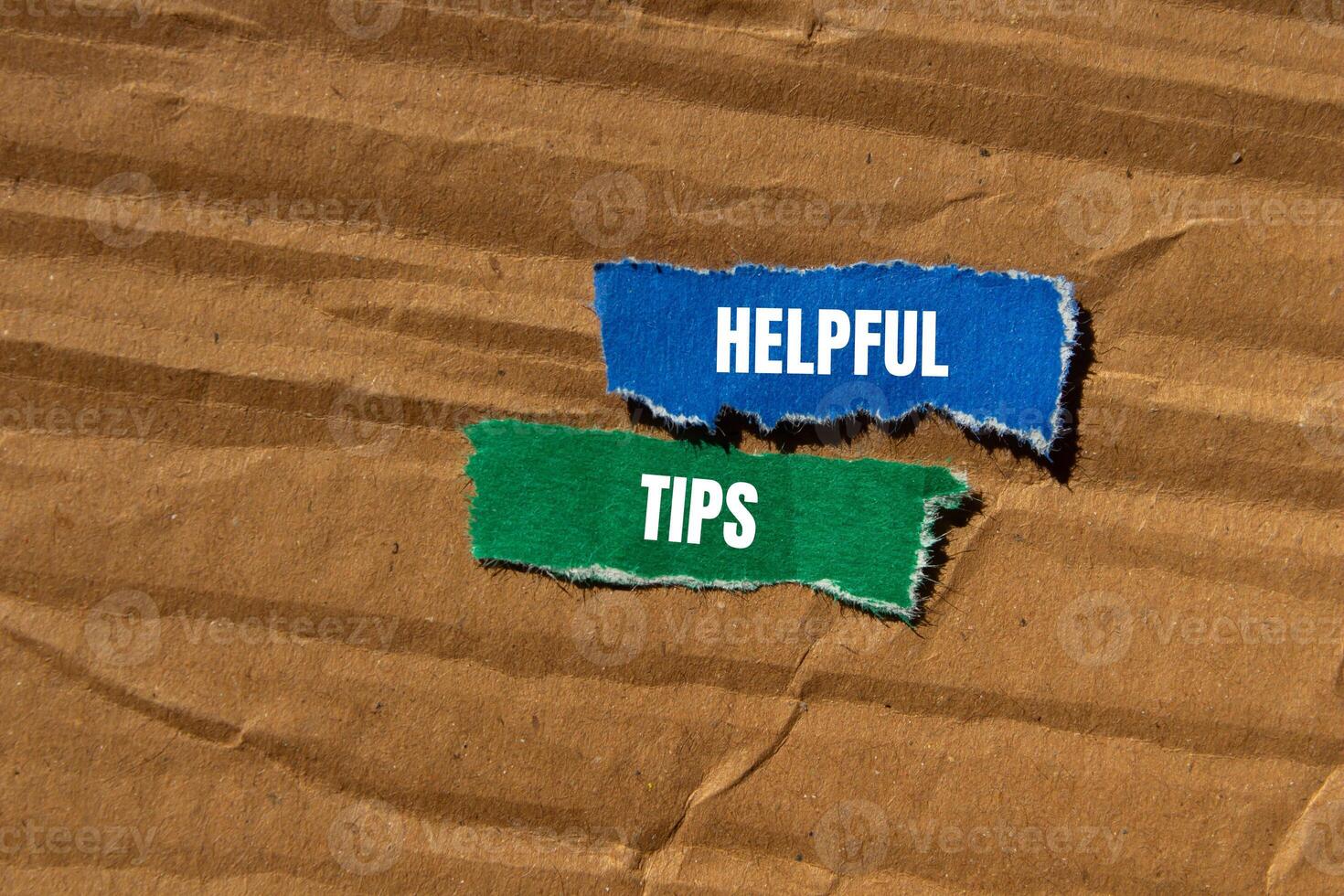 Helpful tips message written on ripped torn paper pieces with cardboard background. Conceptual helpful tips symbol. Copy space. photo