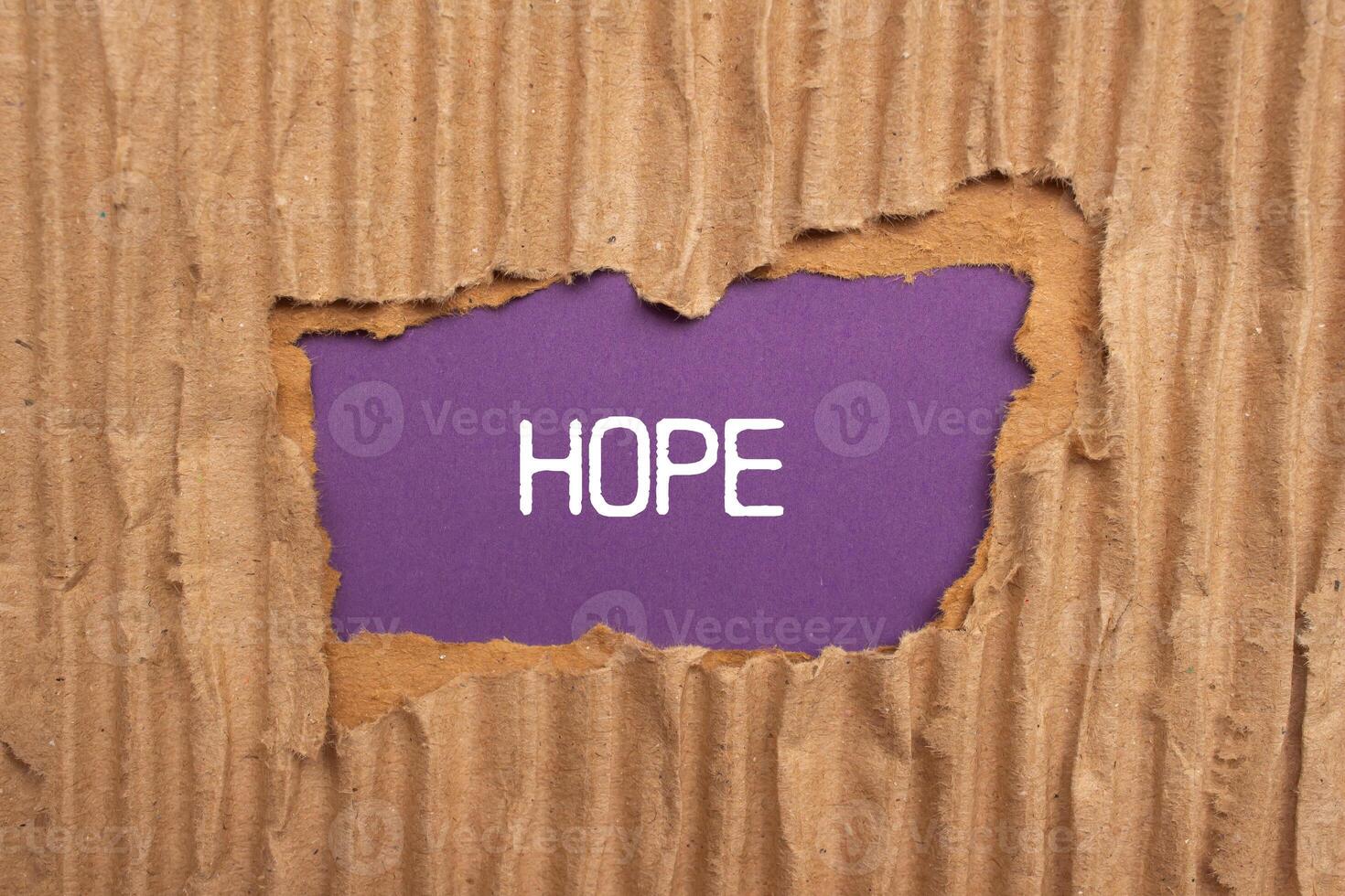 Hope message written on ripped torn cardboard paper with purple background. Conceptual hope symbol. Copy space. photo